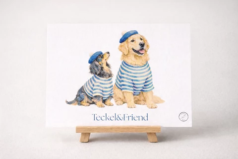 Carte illustrée avec deux chiens stylisés assis côte à côte, en marinières bleues et blanches et bérets bleus, texte « Teckel&Friend » en bas.