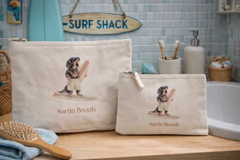 Deux trousses écrues présentent une mascotte canine avec lunettes de soleil et planche de surf, accompagnée du texte Surfin Breizh.