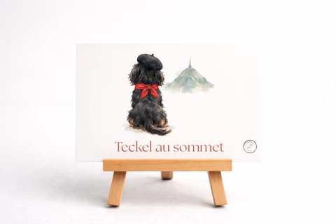 Carte horizontale montrant un petit chien vu de dos, coiffé d’un béret noir et d’un ruban rouge, près d’une colline stylisée.