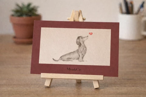 Carte rectangulaire avec un petit chien de profil regardant vers le haut, un cœur rouge au-dessus du museau, encadrement bordeaux et zone centrale claire.